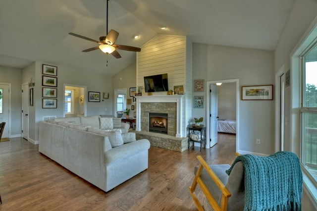 living room featuring ceiling fan, a healthy amount of sunlight, a fireplace, and high vaulted ceiling