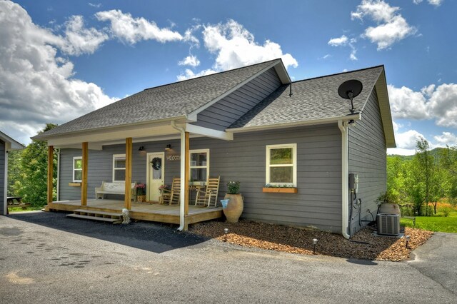 bungalow featuring roof with shingles, central AC unit, and a porch