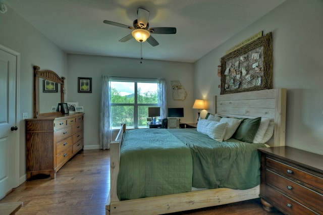 bedroom featuring a ceiling fan, baseboards, and wood finished floors