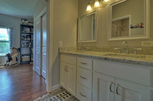 full bath featuring a sink, double vanity, and wood finished floors