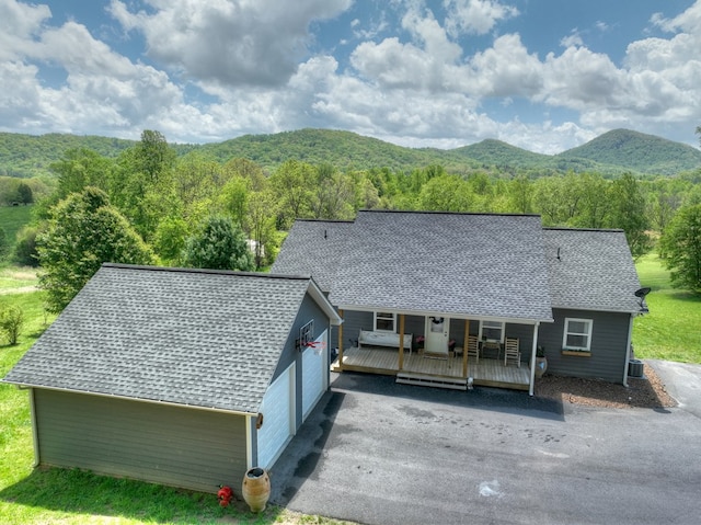 exterior space featuring a porch, a forest view, central air condition unit, a mountain view, and a shingled roof
