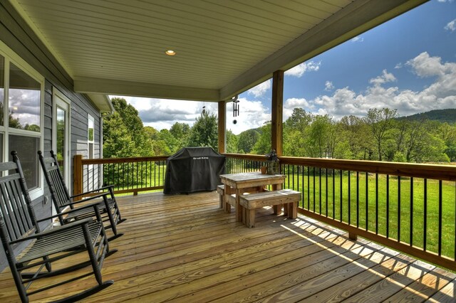 wooden deck featuring a forest view, a yard, and area for grilling