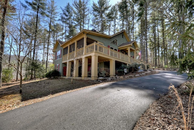 view of front facade featuring aphalt driveway, board and batten siding, and a wooden deck