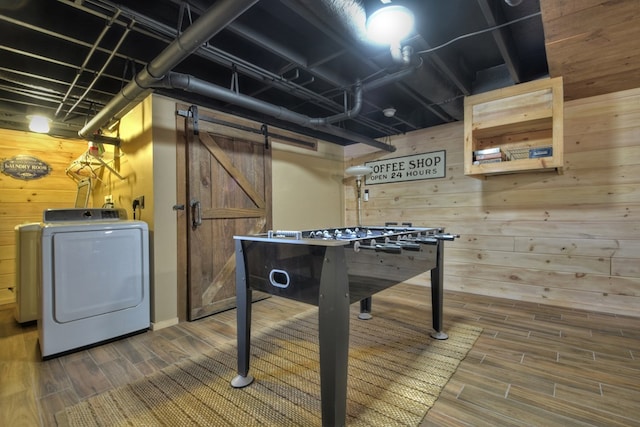 game room with washer / dryer, wood finish floors, wooden walls, and a barn door