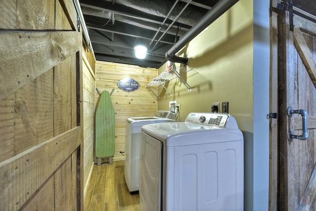 washroom with wood finish floors, wooden walls, and washing machine and clothes dryer