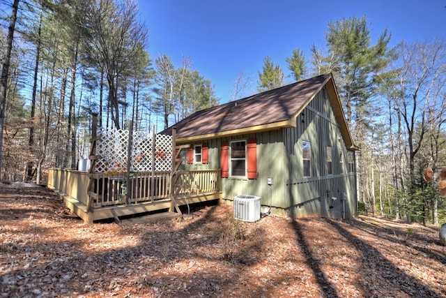 rear view of property with a deck, roof with shingles, and central air condition unit