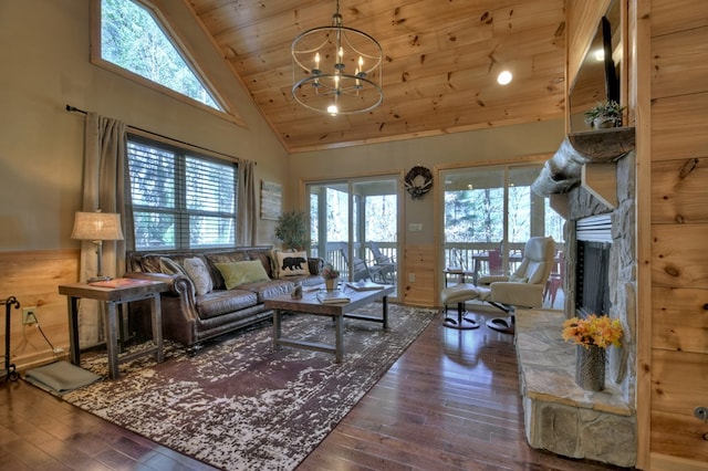 living room with wood ceiling, wood-type flooring, high vaulted ceiling, a stone fireplace, and a chandelier