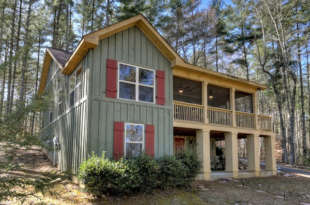 rear view of property featuring board and batten siding, a sunroom, and a patio