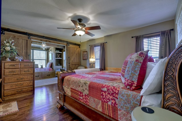 bedroom featuring a barn door, ceiling fan, and wood finished floors