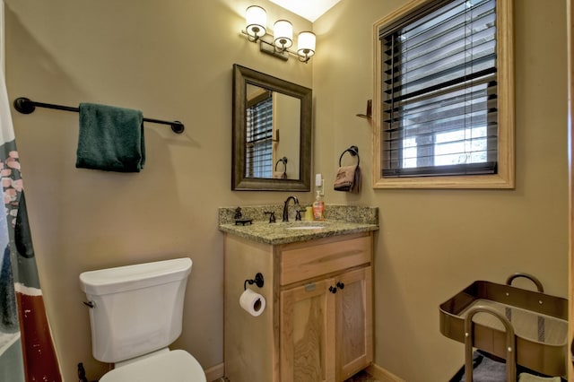 bathroom with baseboards, vanity, and toilet