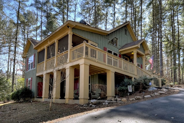 view of side of home featuring a sunroom, a shingled roof, and board and batten siding