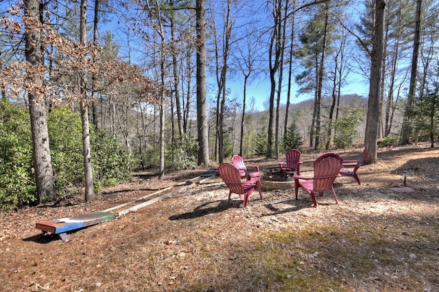 view of yard featuring a fire pit and a wooded view