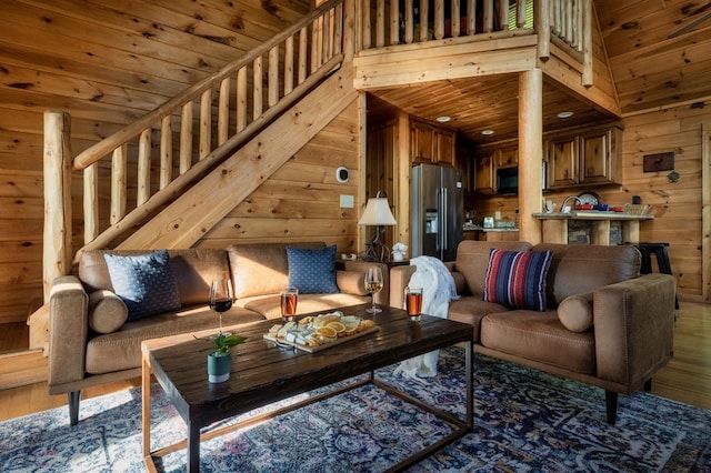 living room with a high ceiling, hardwood / wood-style floors, wood ceiling, and wood walls