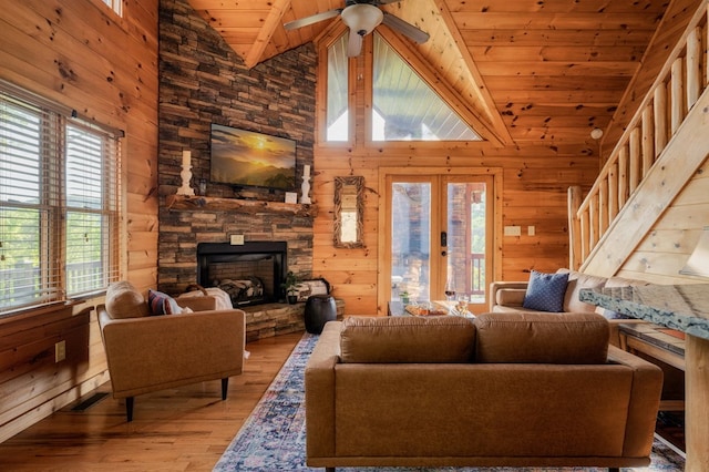 living room featuring a fireplace, wood walls, light hardwood / wood-style flooring, wooden ceiling, and french doors