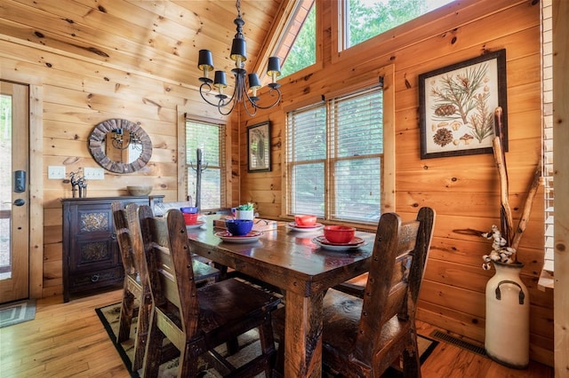 dining space with a chandelier, wood ceiling, wooden walls, and light hardwood / wood-style flooring