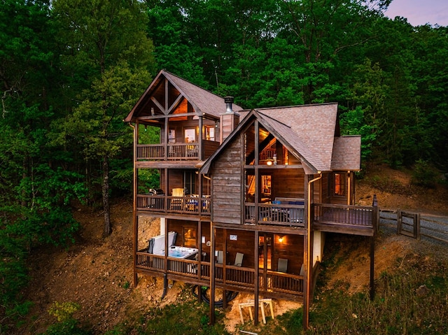 back house at dusk with a jacuzzi and a balcony