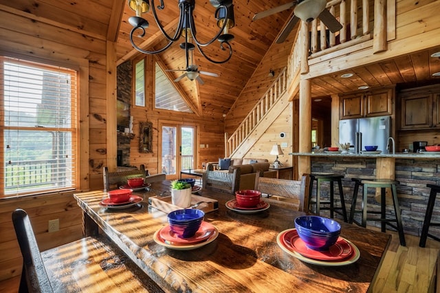 dining space with a healthy amount of sunlight, wooden walls, wooden ceiling, and ceiling fan