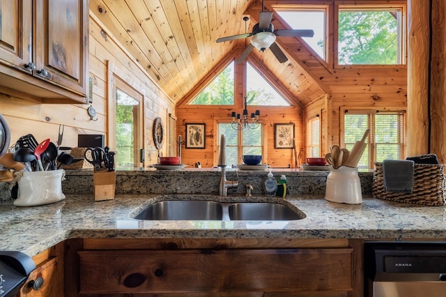 kitchen with plenty of natural light, light stone countertops, dishwasher, and wood walls