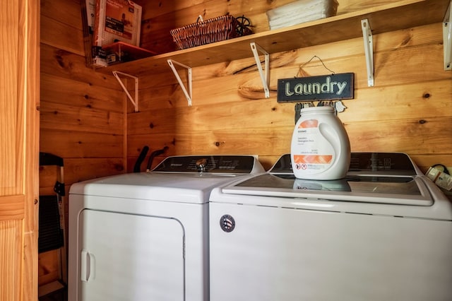 washroom featuring washing machine and clothes dryer and wooden walls