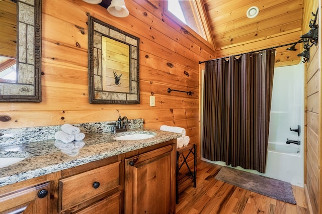 bathroom with hardwood / wood-style floors, wood walls, lofted ceiling, vanity, and shower / tub combo