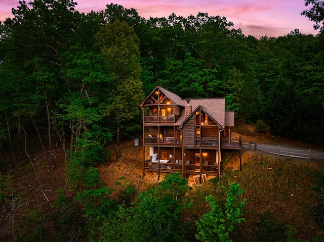 back house at dusk featuring a balcony