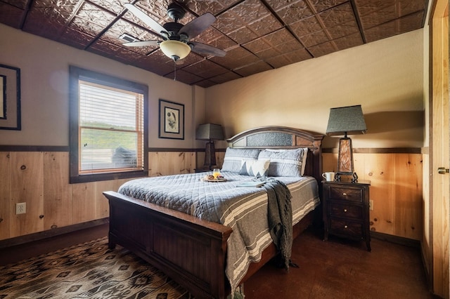 bedroom with ceiling fan and wood walls