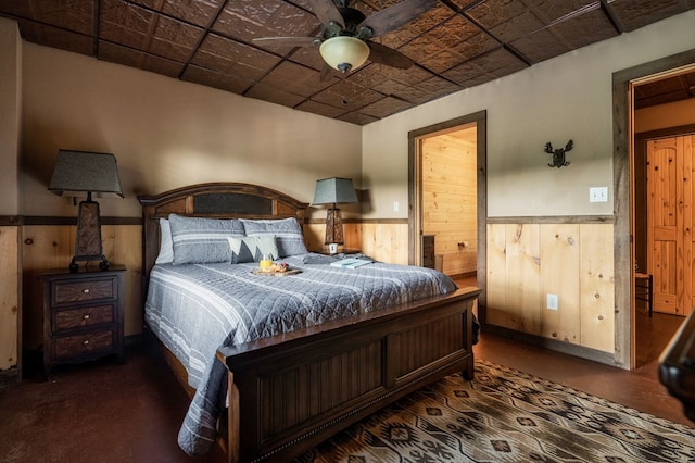 bedroom featuring ceiling fan and wood walls