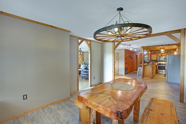 dining area featuring light wood-type flooring, baseboards, and a notable chandelier