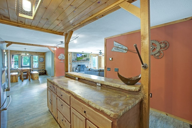 interior space featuring light brown cabinets, a fireplace, open floor plan, ceiling fan, and light wood-type flooring