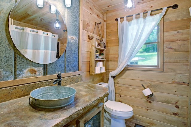 bathroom featuring toilet, wood walls, curtained shower, and vanity