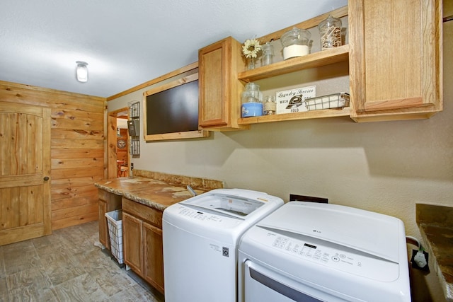 laundry area with wood walls, cabinet space, and washing machine and clothes dryer