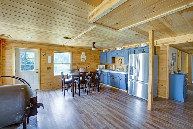 dining room featuring ceiling fan, visible vents, dark wood finished floors, wooden ceiling, and wooden walls