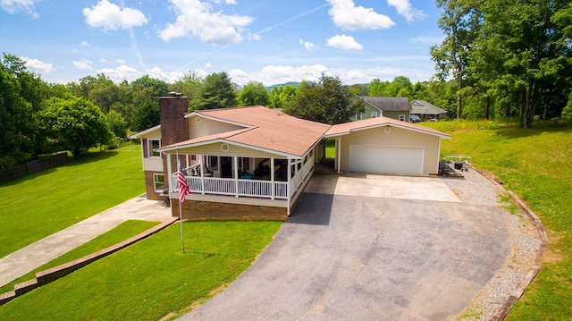 view of front of house featuring an attached garage, a front lawn, a chimney, covered porch, and driveway