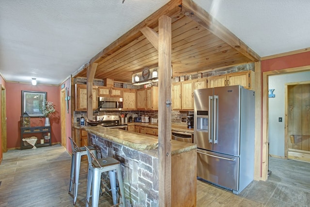 kitchen with baseboards, light wood-style floors, appliances with stainless steel finishes, and a kitchen breakfast bar