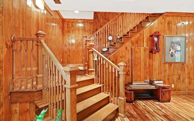 stairs with wooden walls and hardwood / wood-style floors