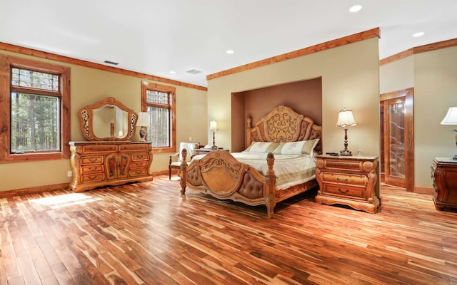 bedroom featuring crown molding, light wood-type flooring, and multiple windows