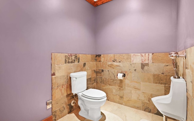 bathroom with toilet, tile floors, and tile walls