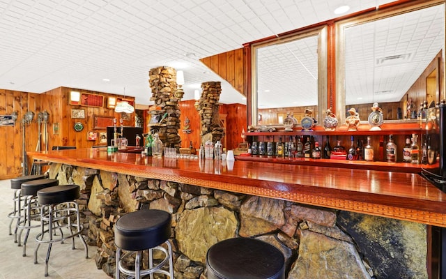 bar with pendant lighting and wood walls