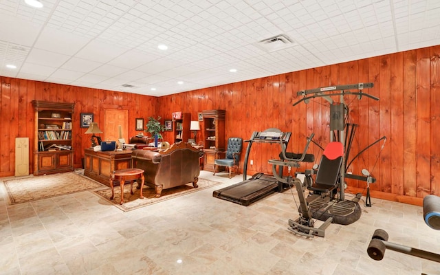 workout room featuring light tile flooring, wooden walls, and a drop ceiling