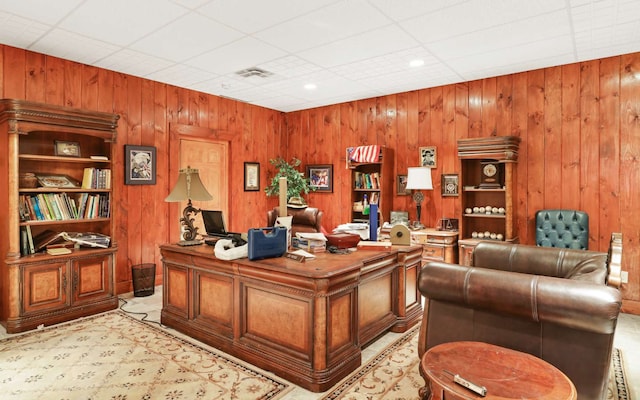 office space featuring light colored carpet, wood walls, and a paneled ceiling