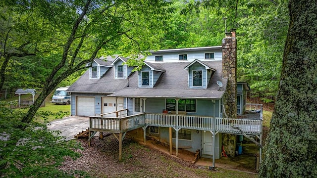 659 Piney Acres Rd, Blue Ridge, GA 30513 - rear view of house featuring a chimney, a wooden deck, driveway, a garage, and a forest view