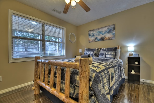 bedroom with ceiling fan, dark hardwood / wood-style floors, and a textured ceiling