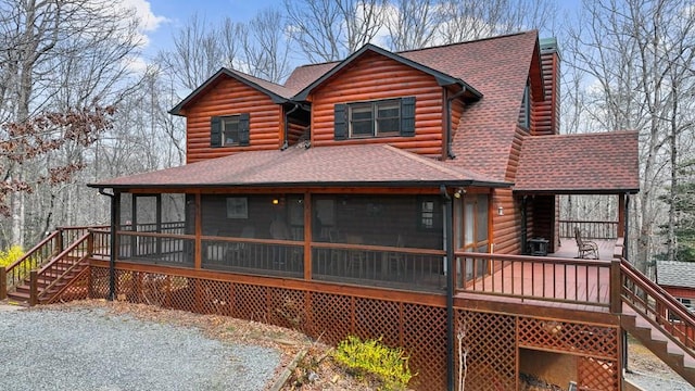 rear view of house with stairway, log exterior, a shingled roof, and a sunroom