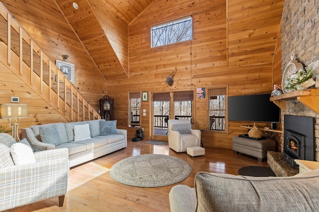 living room with vaulted ceiling, wooden walls, stairway, and hardwood / wood-style flooring