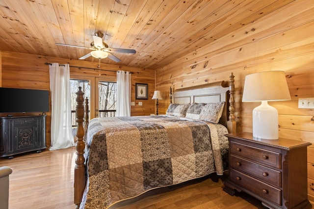 bedroom with a ceiling fan, wood finished floors, wood walls, wood ceiling, and access to exterior