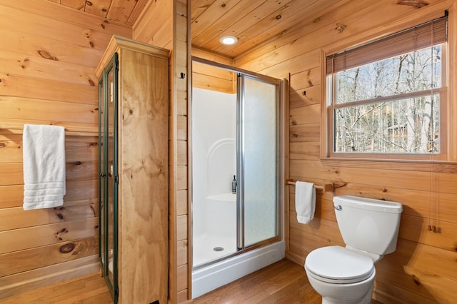 full bath featuring wood walls, wood ceiling, toilet, a stall shower, and wood finished floors