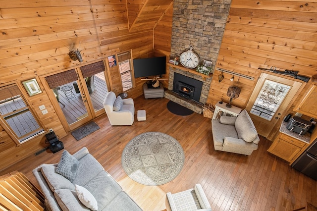 living room featuring wooden walls, high vaulted ceiling, and hardwood / wood-style flooring