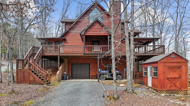 view of front of property with gravel driveway, a shed, an outdoor structure, an attached garage, and log veneer siding