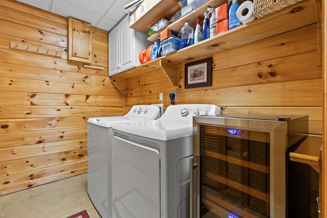 laundry room featuring washing machine and dryer, cabinet space, and wooden walls