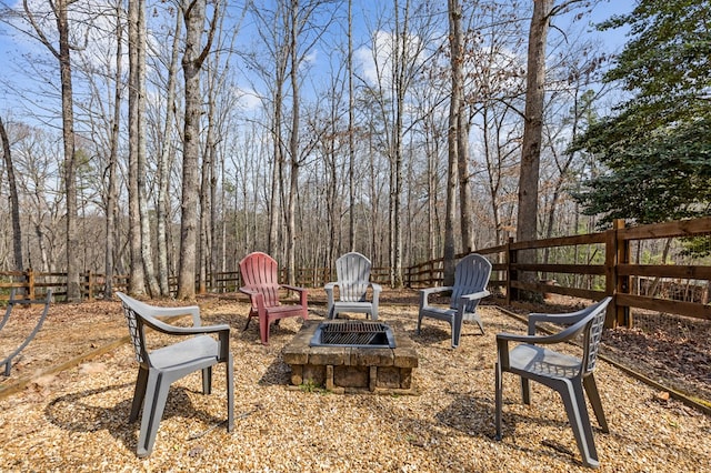 view of yard with an outdoor fire pit, a wooded view, and fence